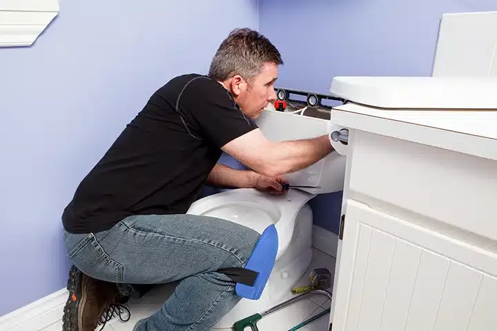 Plumber repairing toilet in residential bathroom in Monroe Township, NJ.